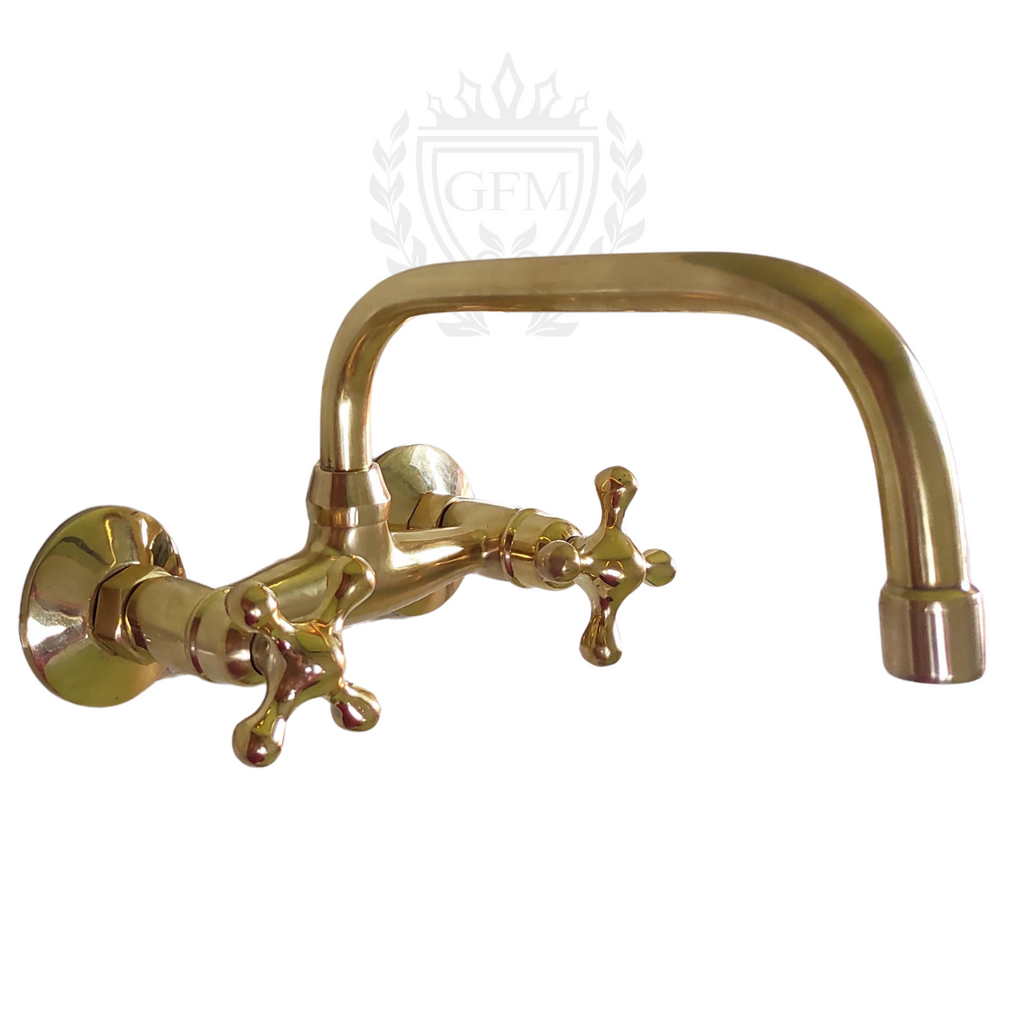 Unlacquered brass wall-mounted bathroom faucet, Side view of vintage brass faucet above vanity sink, Close-up of handmade solid brass faucet with dual handles, Rustic bathroom faucet with warm patina finish, Artisan-crafted brass tap for wall mount installation


